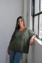 Remera verde militar con cuello en V y mangas 3/4. Presenta apliques circulares con textura en el frente y los hombros.