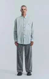 Camisa celeste de manga larga con bolsillo con ojal y botón en el delantero, de calce oversize confeccionada en textil plano fresco y liviano.