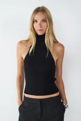 Top negro de punto canalé elástico, sin mangas y con cuello alto. Diseño halter y corte entallado.
