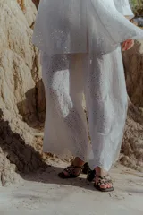 Conjunto de camisa y pantalón blanco con bordado calado. La camisa es de manga 3/4 con botones al frente y calce relajado. El pantalón es forrado con elástico en la cintura.