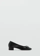 Zapato de cuero negro con tacón bloque y hebilla decorativa.