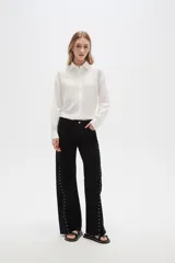 Pantalón jean negro de tiro alto, corte flare y detalle de tachas plateadas en los laterales.