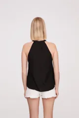 Blusa negra sin mangas con cuello halter y volados en el escote.