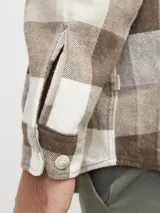 Sobrecamisa a cuadros beige, marrón y blanco, de manga larga y cuello camisero con fit confort. Cierre con botones y bolsillos en el pecho con solapa y broche. Estilo plus size diseñada para cuerpos de talla grande. Tejido de sarga resistente con patrón en “V” característico.