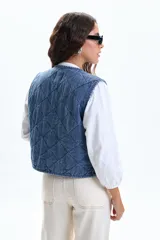 Chaleco sin mangas de jean azul, con diseño acolchado capitoné y cuello en V. Posee dos bolsillos frontales de parche.