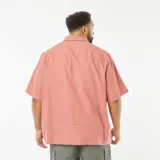 Camisa de manga corta color salmón, con cuello clásico y cierre frontal con botones.