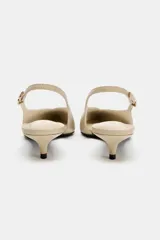 Zapato destalonado tipo slingback color beige, con punta fina, tacón kitten fino y tira trasera ajustable con hebilla metálica.