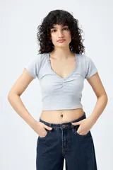 Remera corta negra de punto acanalado con escote en V fruncido y puntilla en el borde.