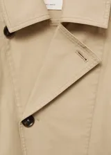 Abrigo color beige con cierre delantero con botones cruzados, cuello camisero, manga larga con trabillas, diseño corto y recto, dos bolsillos laterales y forro interior.