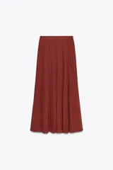 Falda midi color ladrillo, de tiro alto, con plisado fino y estampado de pequeños lunares. Incluye cinturón fino del mismo tejido y forro interior.