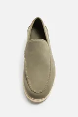 Mocasín casual de hombre color verde oliva, fabricado en cuero con acabado serraje, corte liso con detalle de bordón, horma redonda y suela a contraste color crema.
