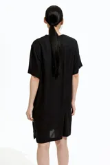 Vestido túnica negro a la rodilla en tejido liviano de viscosa con cuello mao y abertura en V. Modelo de corte holgado con hombros levemente caídos, mangas cortas y bajo recto con tajos laterales.