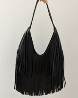 Bolso de hombro negro con diseño de flecos largos que cubren la mayor parte del cuerpo del bolso. Tiene un asa corta y curva.