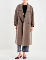 Tapado largo de paño texturado color gris topo, de corte oversize y doble botonadura. Presenta cuello con solapas anchas y mangas largas con puños doblados.