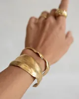 Brazalete rígido plateado con textura irregular.