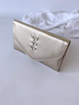 Billetera dorada de cuero con diseño trenzado y cierre con broche, incluye monedero externo.