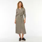 Vestido camisero largo con estampado geométrico en tonos beige, negro y blanco. Tiene cuello camisero, mangas largas con puños abotonados, cierre frontal con botones y cinturón de lazo.
