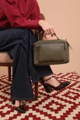 Bandolera color marrón con asa superior y correa larga ajustable. Tiene dos bolsillos frontales, uno de ellos con cierre cruzado.