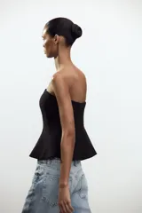 Top negro palabra de honor con peplum, confeccionado en tejido elástico con forro interior y cierre de cremallera oculta en la costura.