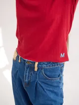 Polera negra de tela rib con cuello alto y mangas largas. Presenta pespuntes rojos en cuello, hombros y puños.