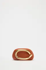 Bolso marrón con forma de caja, con cierre dorado en forma de C y asa de cadena dorada para usar como bandolera.