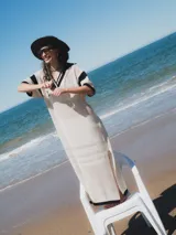 Remerón tejido color crudo, con calados y cuello estilo camisa, de corte largo y mangas cortas con terminación en rib.