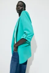 Blazer marrón con cuello solapa y hombreras. Manga tres cuartos con trabilla y botón dorado. Bolsillos delanteros con solapa.