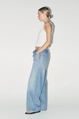 Pantalón de jean celeste de tiro alto, corte wide leg y largo hasta el tobillo. Incluye cinturón de la misma tela con trabillas y cierre frontal con cremallera, botón y gancho metálico.