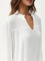 Blusa celeste con cuello mao y escote en V, de mangas largas con puños elásticos.