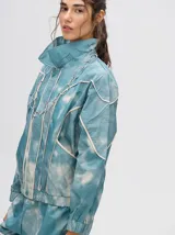 Campera rompevientos estilo biker con capucha desmontable, color celeste con estampado de nubes blancas y detalles en blanco.