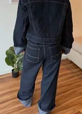 Pantalón de jean azul oscuro de corte ancho con dobladillo en color gris claro.