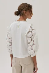 Blusa blanca de mangas 3/4 con bordado calado y cuello redondo con volados.