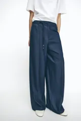 Pantalón de tiro alto azul denim, con cintura elástica ajustable con cordón, bolsillos laterales y traseros, y pernera ancha.