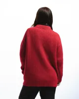 Sweater unisex de lana merino fina color rojo, con cuello redondo y corte relajado. Presenta un motivo inspirado en la técnica de zurcido visible.