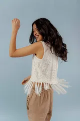 Chaleco de hilo color crema, con cuello redondo y diseño calado. Presenta flecos en el ruedo.