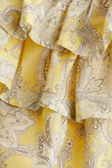 Minifalda amarilla con estampado paisley en tonos grises y cintura elastizada. Presenta volados en capas.
