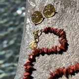 Aros tipo botón dorados con textura irregular que simula la superficie de un molusco.