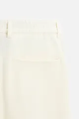 Pantalón color crudo de tejido con textura de rizo, corte relaxed fit, con cintura elástica, bolsillos frontales y traseros, cierre frontal con cremallera y botón.