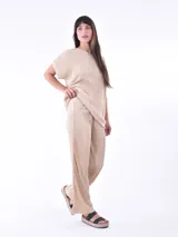 Pantalón de vestir color beige claro, de corte palazzo y tejido plisado.