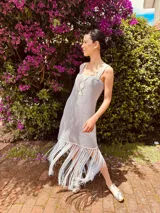 Vestido corto tejido en lurex con diseño geométrico en cuero en el frente, breteles de cuero intervenido a mano con tientos de cuero plateado y terminación en flecos.