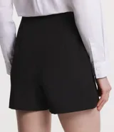 Shorts negros de sastrería con detalle de botones en los laterales y pliegues.