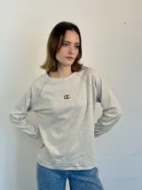 Remera manga larga color gris claro, de jersey 100% algodón, con corte holgado, mangas relaxed, largo a la cadera, bordado con logo en el frente y pespuntes en contraste.