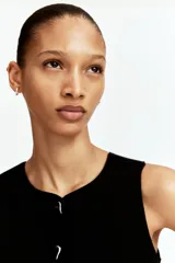 Chaleco negro entallado de punto suave, con cuello redondo y botones metálicos plateados en el frente.