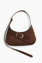 Cartera marrón de hombro con correa ajustable, cierre magnético oculto y trabilla decorativa con hebilla de metal dorada. La correa tiene un extremo extralargo para poder usar como bandolera.