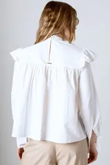Blusa blanca de mangas largas con cuello alto con volados y detalles de encaje.