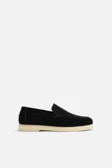 Mocasín casual de hombre color negro, con capellada de cuero serraje, corte liso con detalle de bordón y suela color crema.