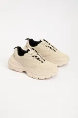 Zapatillas deportivas color beige con detalles en negro, de estilo chunky y suela track.