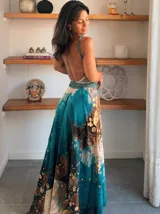 Vestido largo de tela fluida, color verde esmeralda con estampado abstracto en tonos turquesa y detalles dorados. Diseño asimétrico con un solo tirante tejido en el hombro.