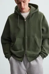 Sudadera negra con capucha ajustable, corte relaxed fit, confeccionada en tejido de algodón compacto con interior en rizo. Cuenta con manga larga, bolsillos frontales tipo canguro, acabados en rib y cierre frontal con cremallera.