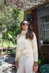 Sweater tejido a mano en lana merino color crema, con cuello alto tipo polerón y mangas largas.